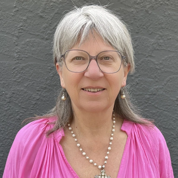 Jackie Picture of Jackie Saunders, lady in pick dress, silver hair, grey glasses.